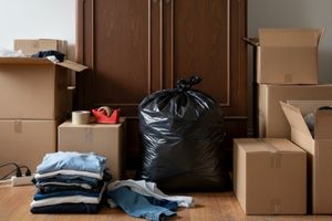 Wäschesack mit Kleidung darin steht vor Schrank